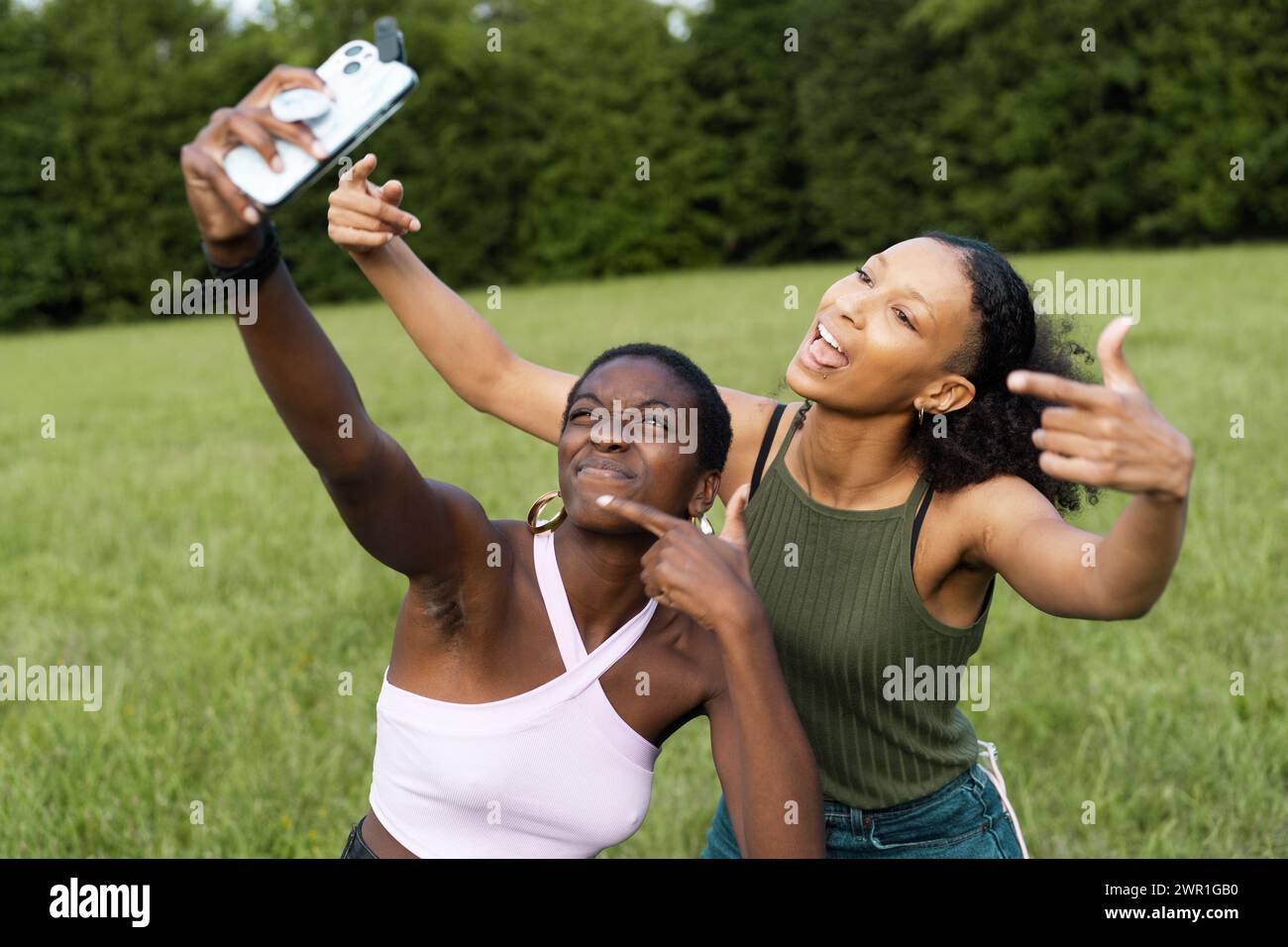 Die besten afrikanischen Freundinnen, die im Freien ein freudiges Selfie machen - Feier der Freundschaft inmitten von Grün. Stockfoto