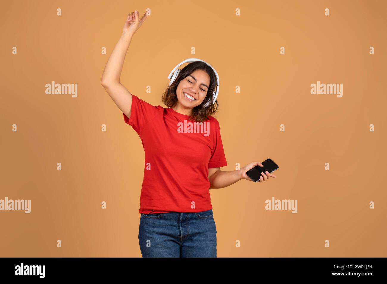 Fröhliche junge Frau aus dem Nahen Osten, die Musik hört Stockfoto