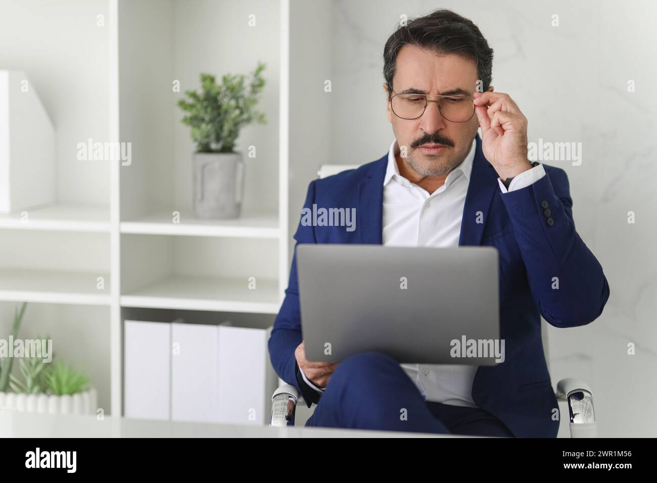 Konzentrierter Geschäftsmann mit Brille und Blick auf den Laptop-Bildschirm Stockfoto