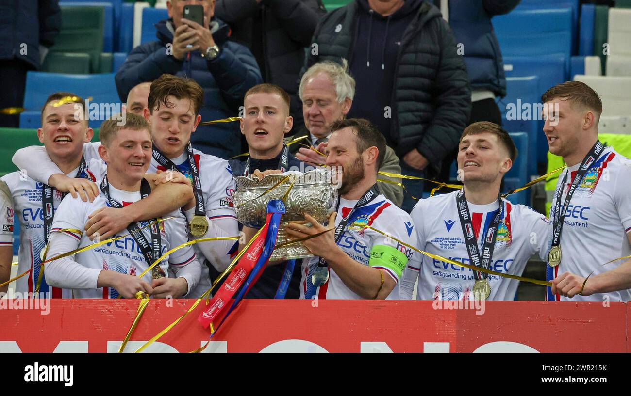 National Football Stadium im Windsor Park, Belfast, Nordirland, Großbritannien. März 2024. Finale des BetMcLean League Cup – Linfield gegen Portadown. (Linfield in weiß). Linfield-Kapitän Jamie Mulgrow mit dem Pokal und den BetMcLean League Cup-Sieger Linfield. Quelle: CAZIMB/Alamy Live News. Stockfoto