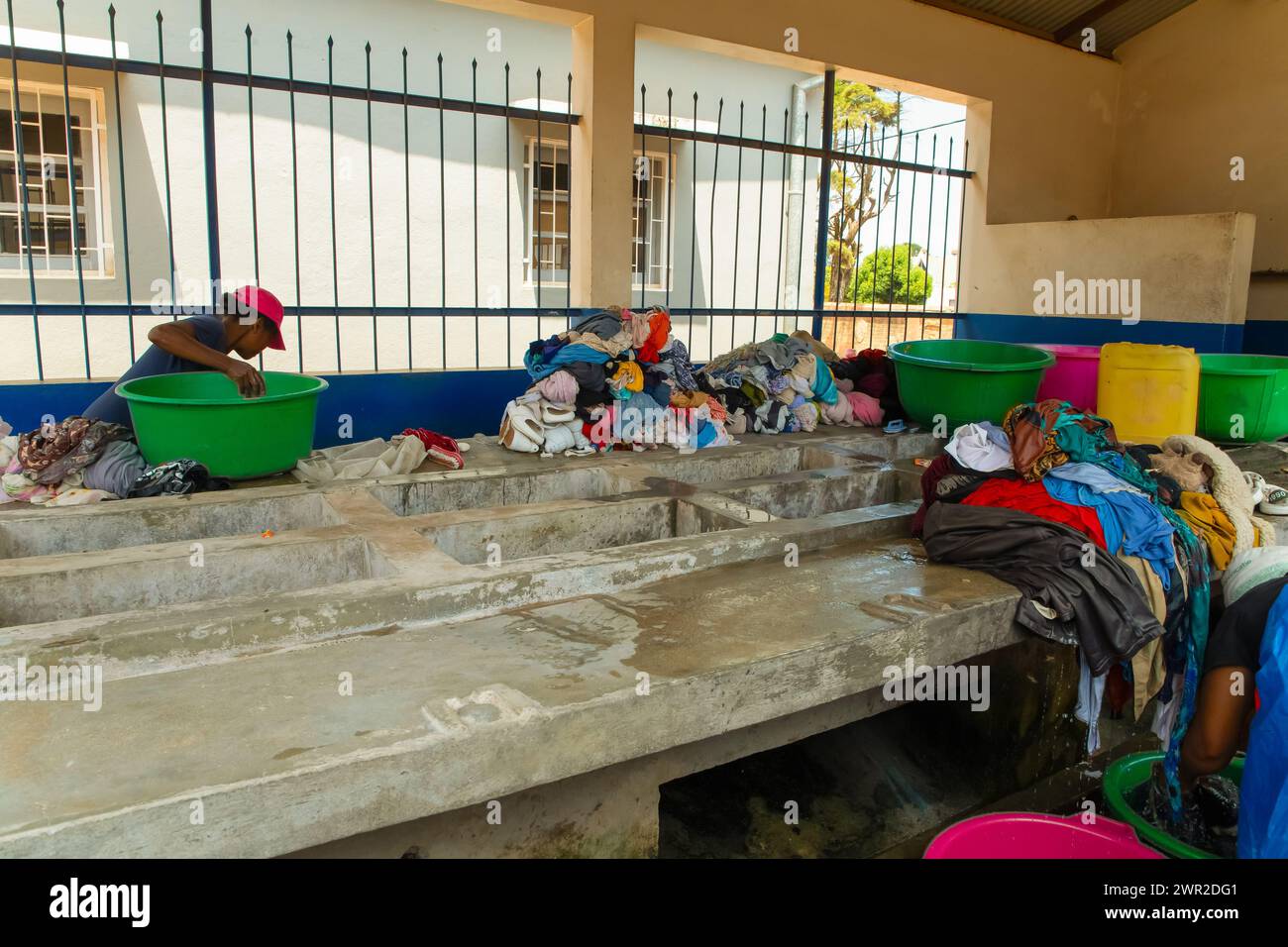 Antananarivo, Madagaskar. Oktober 2023. Wäscherei in Antananarivo. Betonblock mit Waschbecken in der Nähe, in der Frauen Kleidung waschen. Stapel von gewaschenen nassen Tüchern Stockfoto