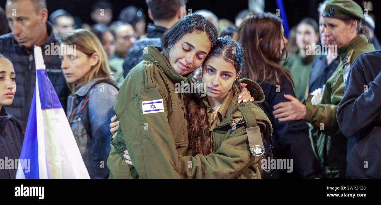 Jerusalem, Israel. März 2024. Menschen in der Nähe des frischen Grabes von Michael Gal, der im Krieg mit dem Eisernen Schwert zwischen Israel und der Hamas getötet wurde. Das Foto zeigt zwei traurige Mädchen, Soldaten, die sich gegenseitig umarmen. Im Hintergrund sind viele andere traurige Trauer. Quelle: Yoram Biberman/Alamy Live News. Stockfoto