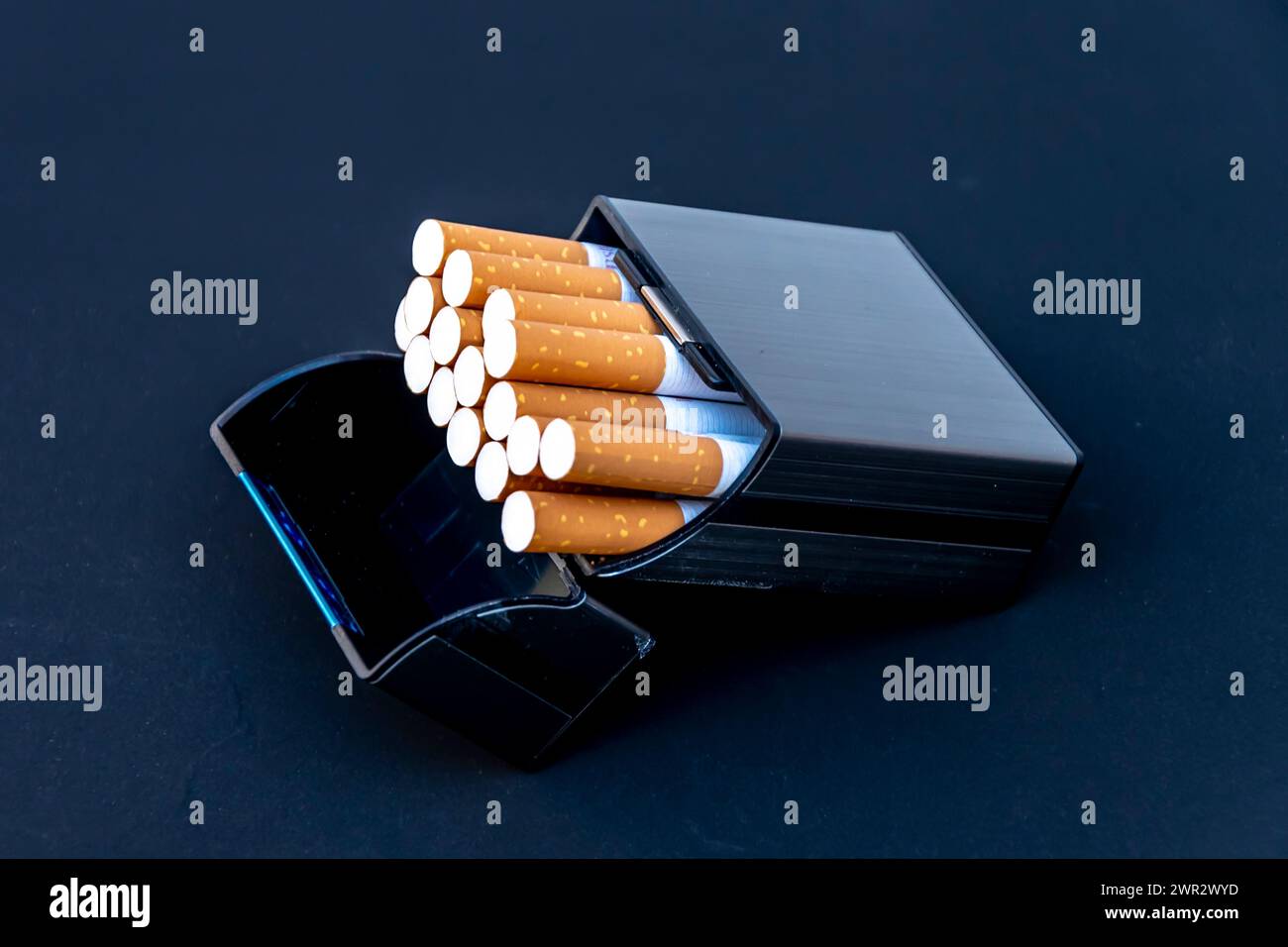 Zigaretten in einem silbernen Zigarettenetui in Form einer Zigarettenpackung auf schwarzem Hintergrund. Stockfoto