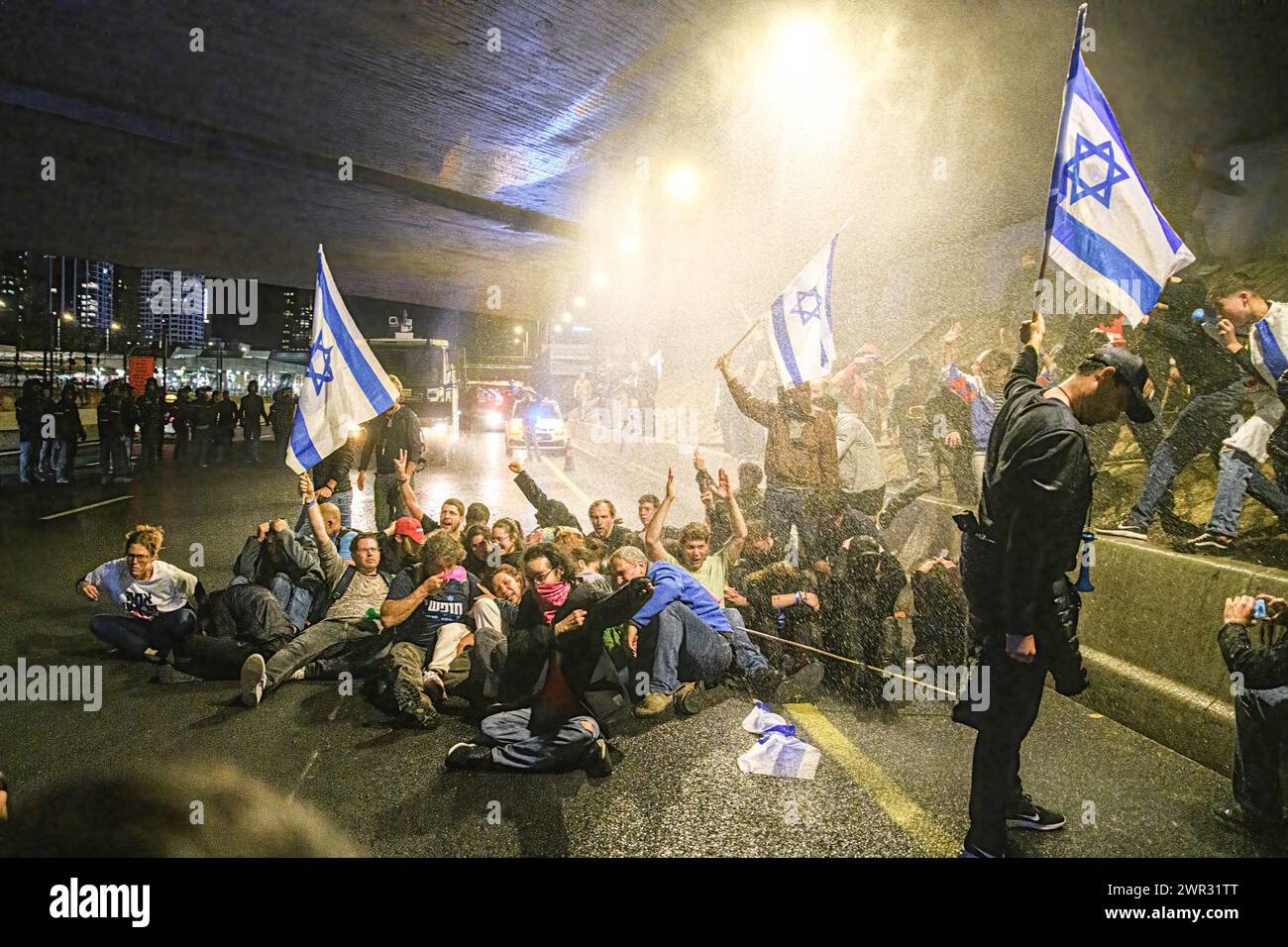 Tel Aviv, Israel. März 2024. Demonstranten blockieren den Ayalon Highway, da die Polizei Wasserwerfer benutzt, um sie während der Demonstration zu zerstreuen. Tausende Israelis protestierten gegen Premierminister Benjamin Netanjahu und seine rechtsextreme Regierung, die eine sofortige Freilassung von Geiseln und allgemeine Wahlen im Staat Israel forderten. Während der Demonstration durchbrachen Demonstranten die israelischen Polizeibarrieren und es kam zu Auseinandersetzungen zwischen der Polizei und den Demonstranten. (Credit Image: © Matan Golan/SOPA Images via ZUMA Press Wire) NUR REDAKTIONELLE VERWENDUNG! Nicht für kommerzielle ZWECKE! Stockfoto