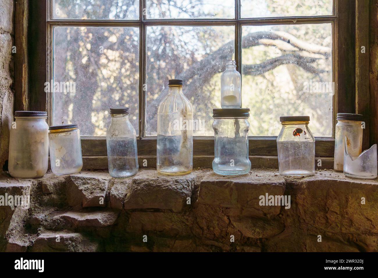 Alte antike Glasflaschen sitzen in einer Reihe auf einer Fensterbank der Eagle Cliff Mine Hütte im Joshua Tree National Park, Kalifornien Stockfoto