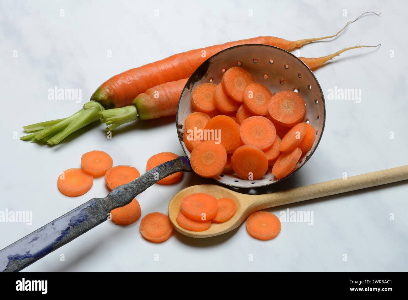 Karottenscheiben in Sieb und Holzlöffel, Daucus carota Stockfoto