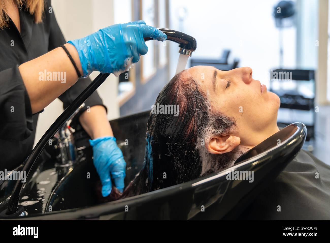 Friseurin wäscht das Haar einer Frau in einem Waschbecken in einem Schönheitssalon Stockfoto