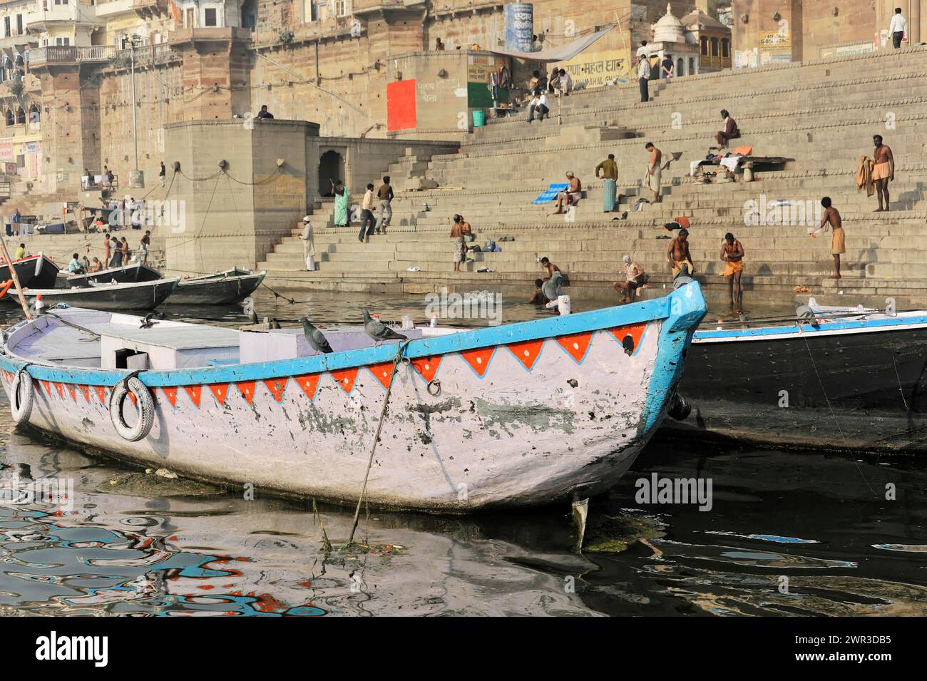 Vor einem Boot auf ruhigem Wasser, im Hintergrund eine lebhafte Stadt am Ufer, Varanasi, Uttar Pradesh, Indien Stockfoto