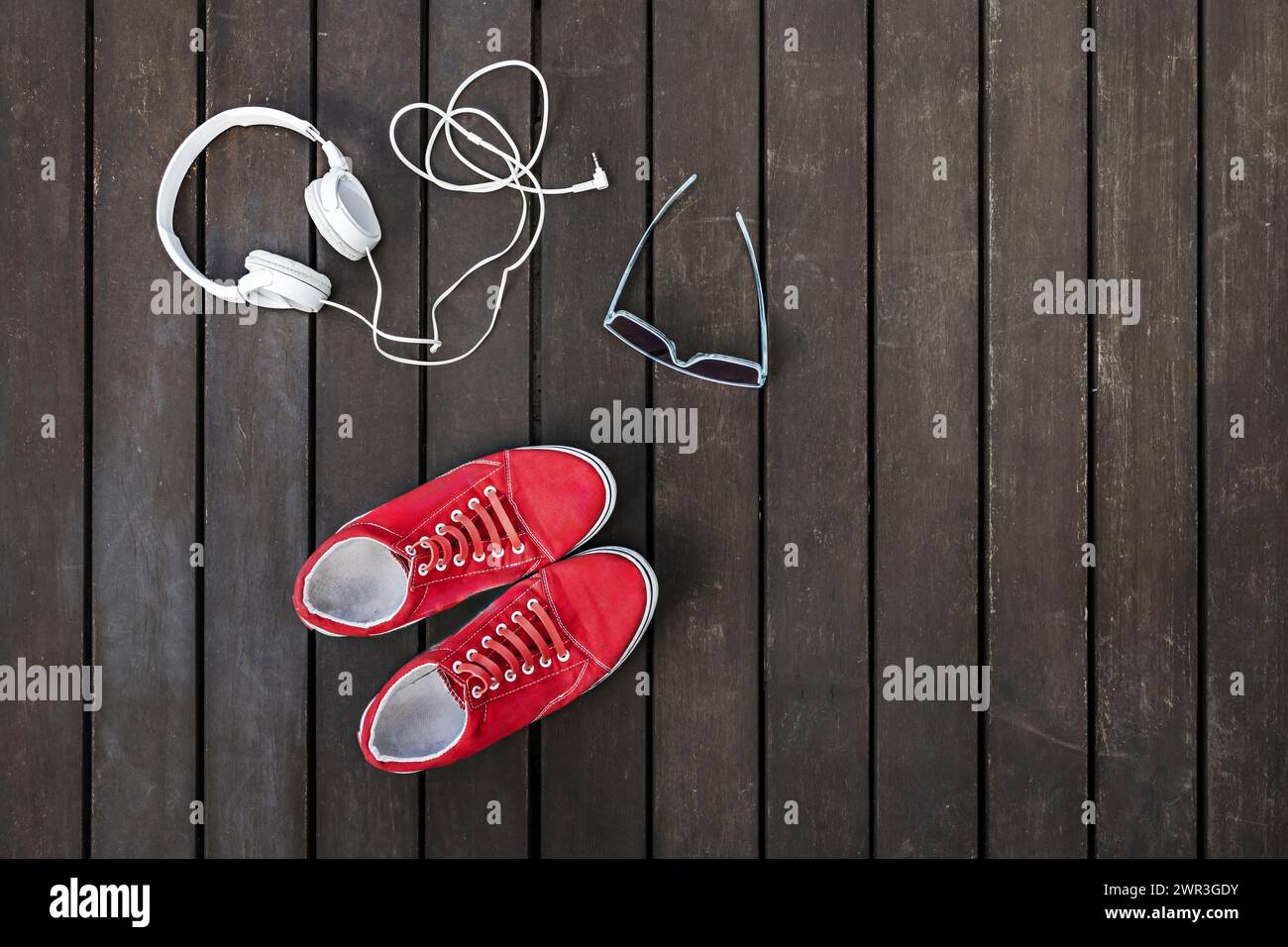 Rote Sneakers mit Kopfhörern und Sonnenbrille Stockfoto