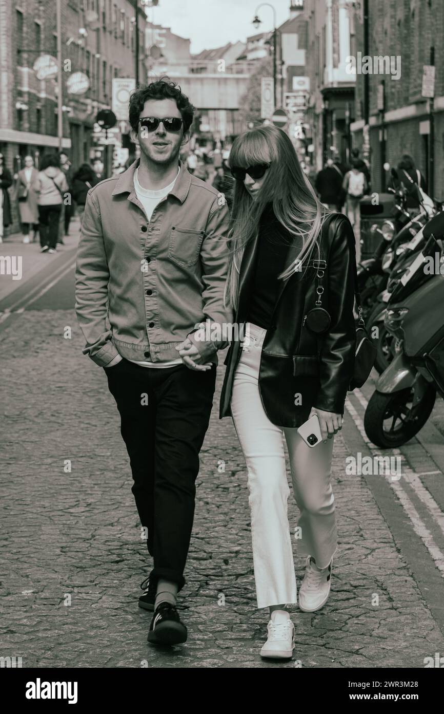 Ein Paar spaziert entlang der Brick Lane in London im Stil der 60er Jahre Stockfoto