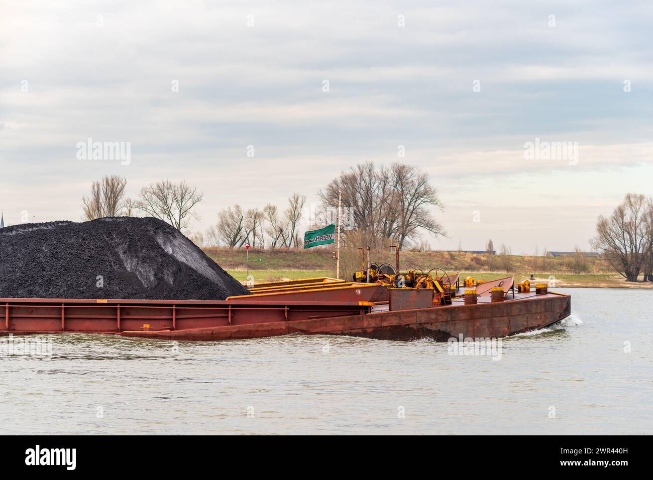 NIJMEGEN, NIEDERLANDE - 9. MÄRZ 2024: Riesiger niederländischer Lastkahn, der mit einer Ladung schwarzen Sandes auf dem Waal fährt Stockfoto