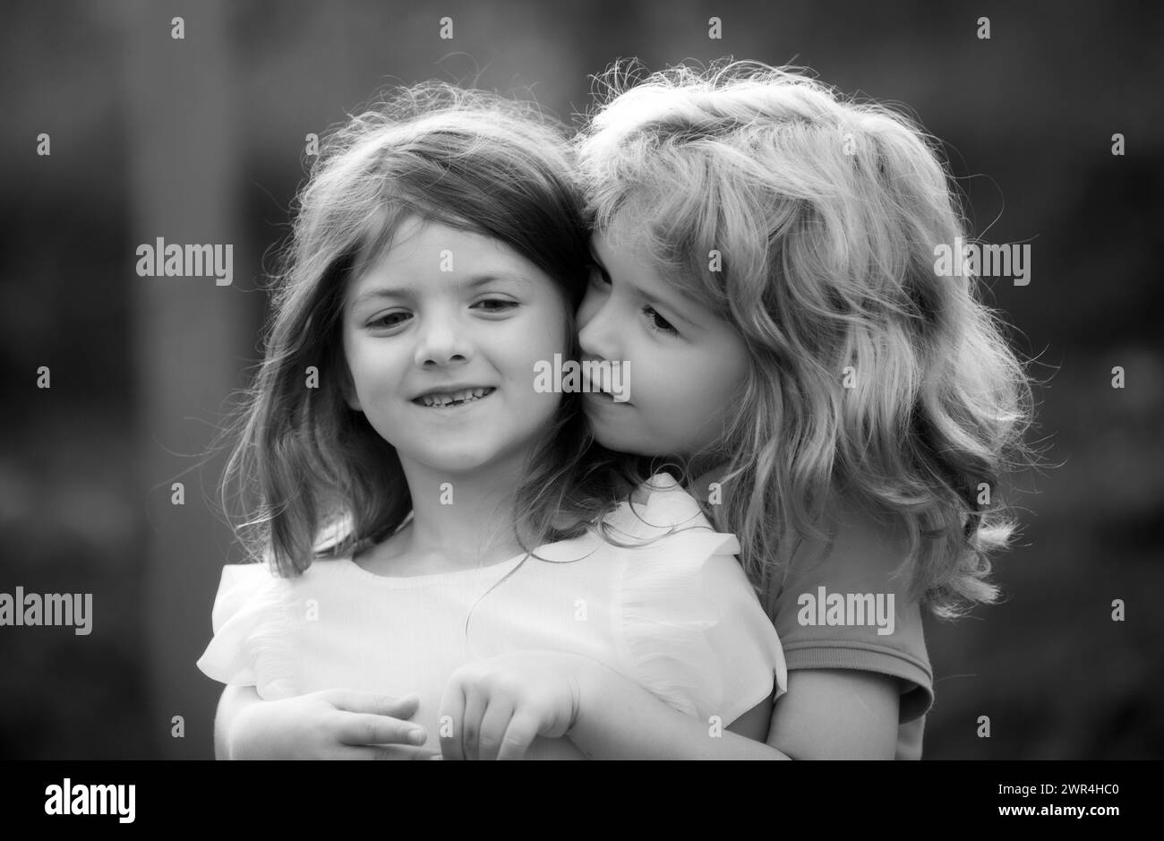 Zwei kleine Kinder umarmen und küssen sich im Sommergarten. Kinder verlieben sich. Freundschaft und Kindheit. Stockfoto