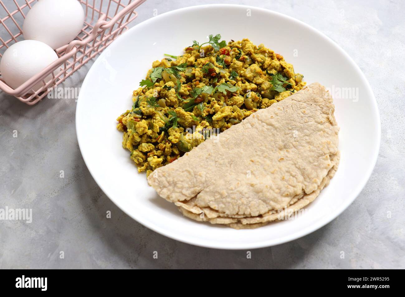 Anda Masala Bhurji oder scharfe indische Rührei mit Brot oder Bun Pav, ein beliebtes Street Food in Mumbai. Serviert auf weißem Teller mit Kopierraum Stockfoto