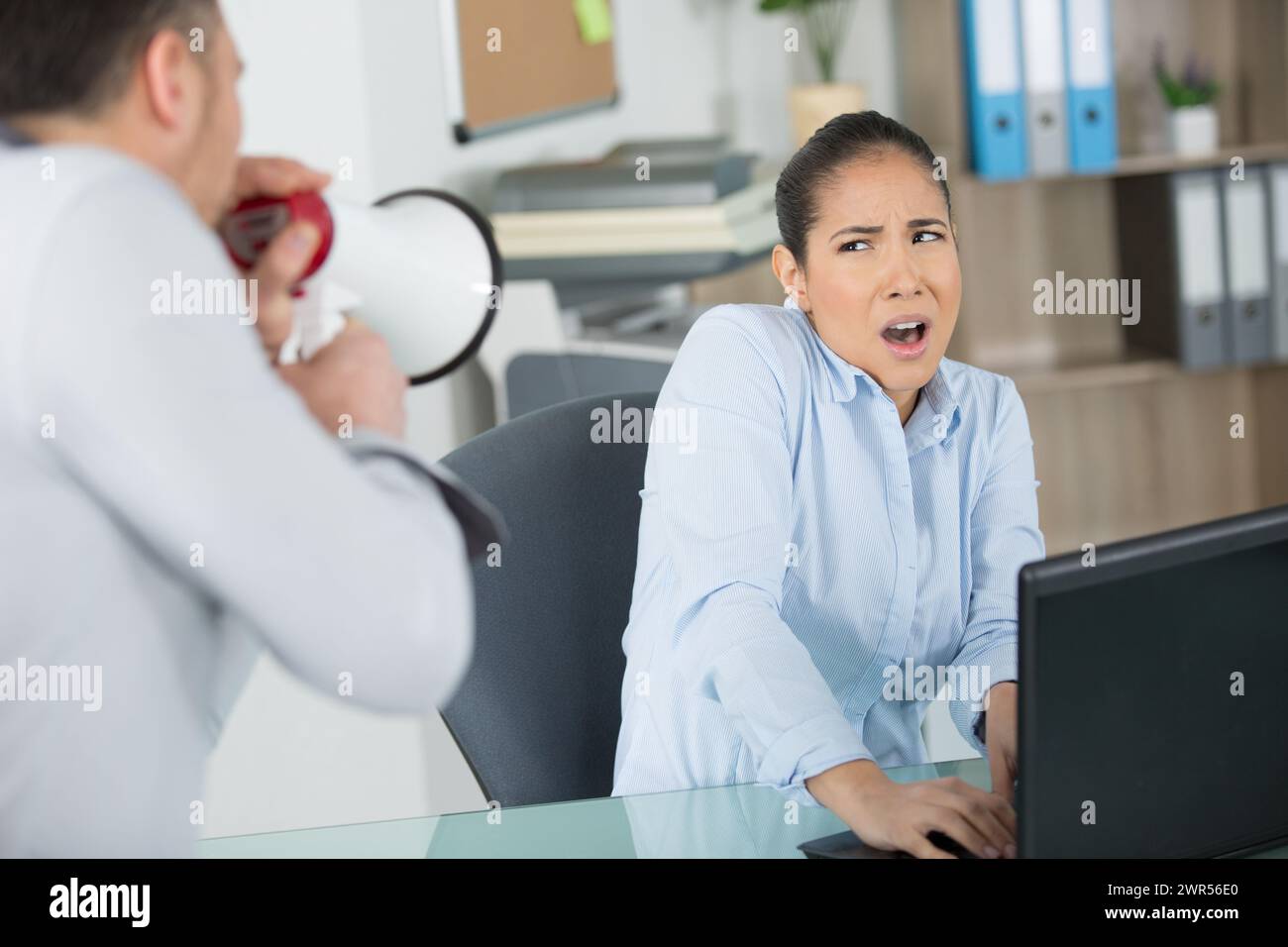 Der Boss ruft Büroangestellte durch ein Megaphon an Stockfoto
