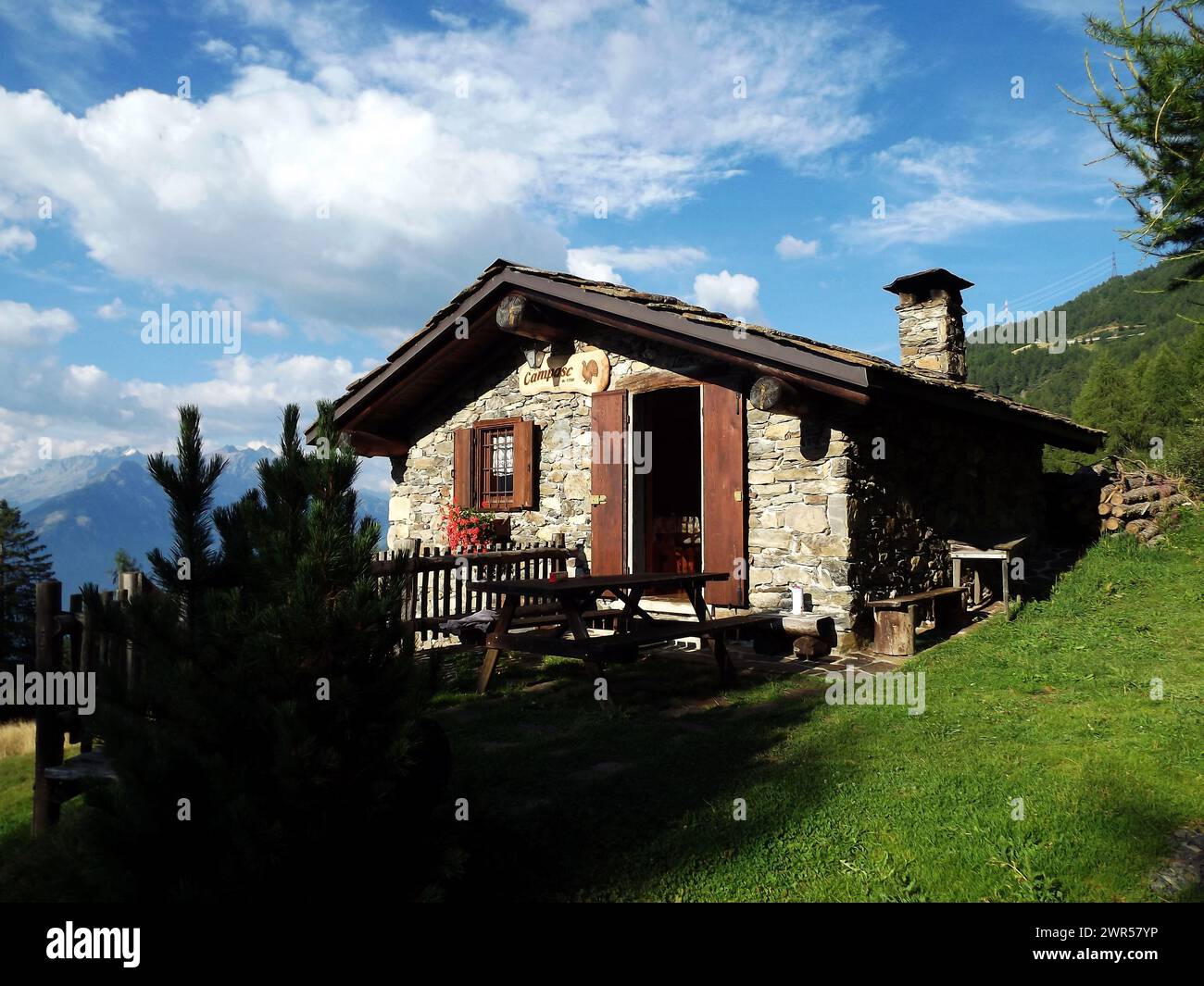 Berghütte in den Alpen. Kleines Berghaus im Sommer mit Bergpanorama, im Wald, umgeben von Natur im Sommer. Blauer Himmel, sonniger Tag. Stockfoto