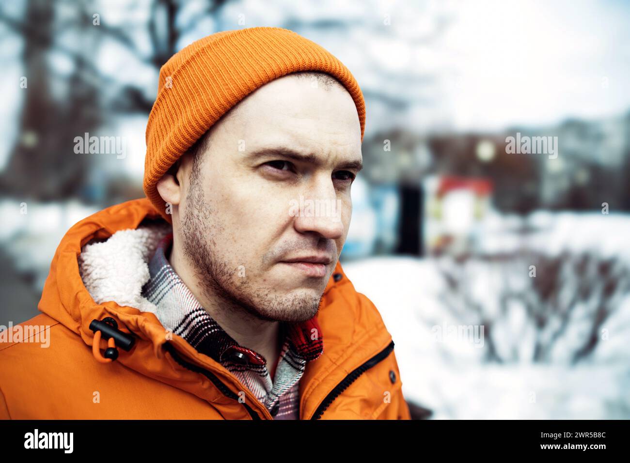 Mann mit orangefarbener Jacke und Mütze. Stockfoto