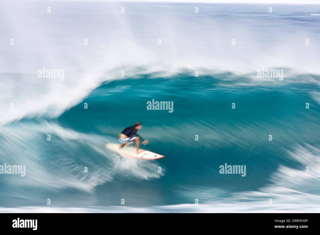 Ein schwacher Blick auf einen jungen Mann, der in Pipeline, Hawaii, surft Stockfoto