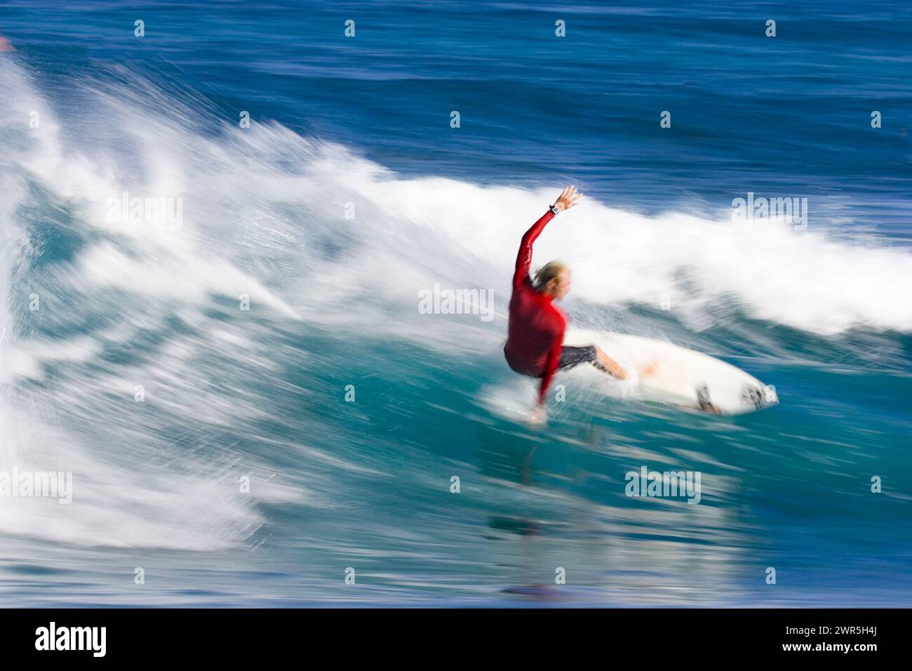 Ein schwacher Blick auf einen jungen Mann, der am Rocky Point am Nordufer von Oahu, Hawaii, surft. Stockfoto