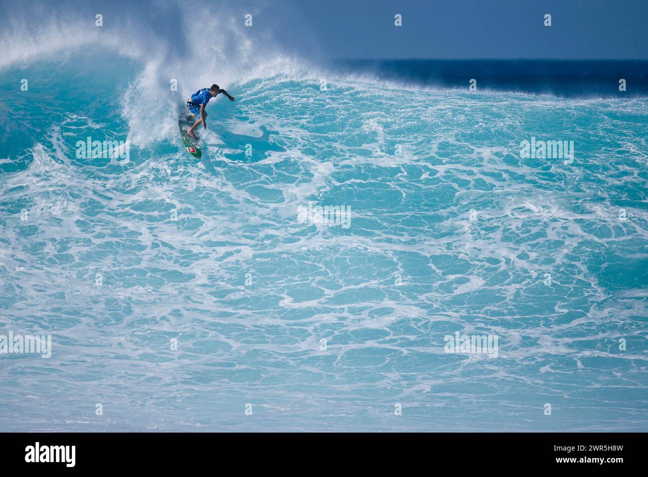Ein junger Mann, der auf einer riesigen Welle in Pipeline surft, am Nordufer von Oahu, Hawaii Stockfoto