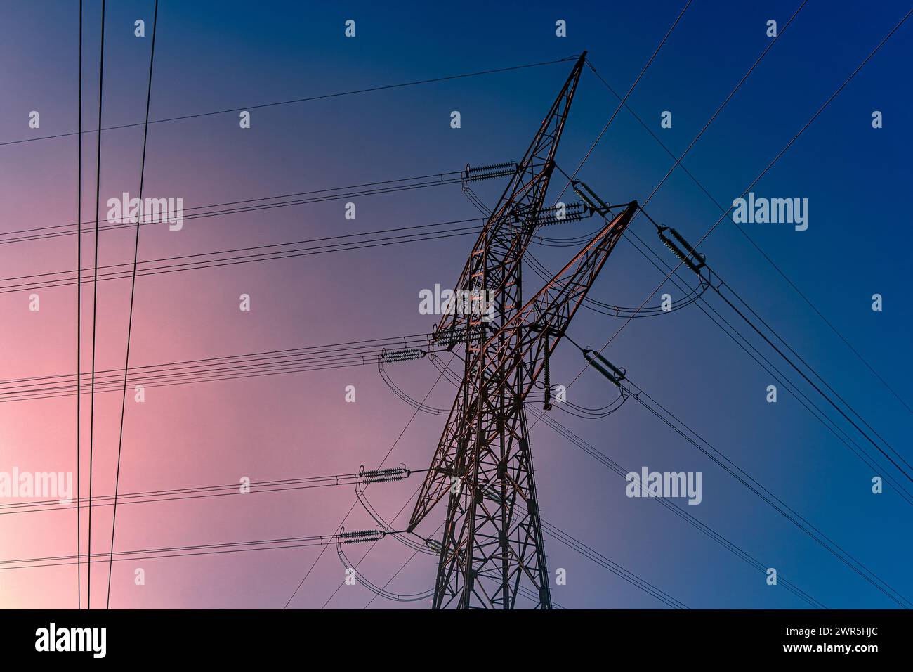 Metallischer Pylon mit Hochspannungsstrom, blauem und rotem Himmel, Morgenfarben. Frankreich, Europa Stockfoto