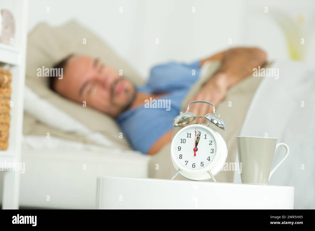 Wecker aufwachen schlafenden Mann im Bett Stockfoto