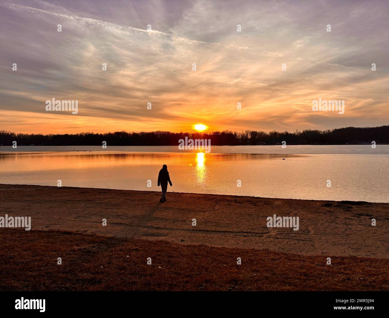 Person, die den See mit Sonnenuntergang entlang läuft Stockfoto