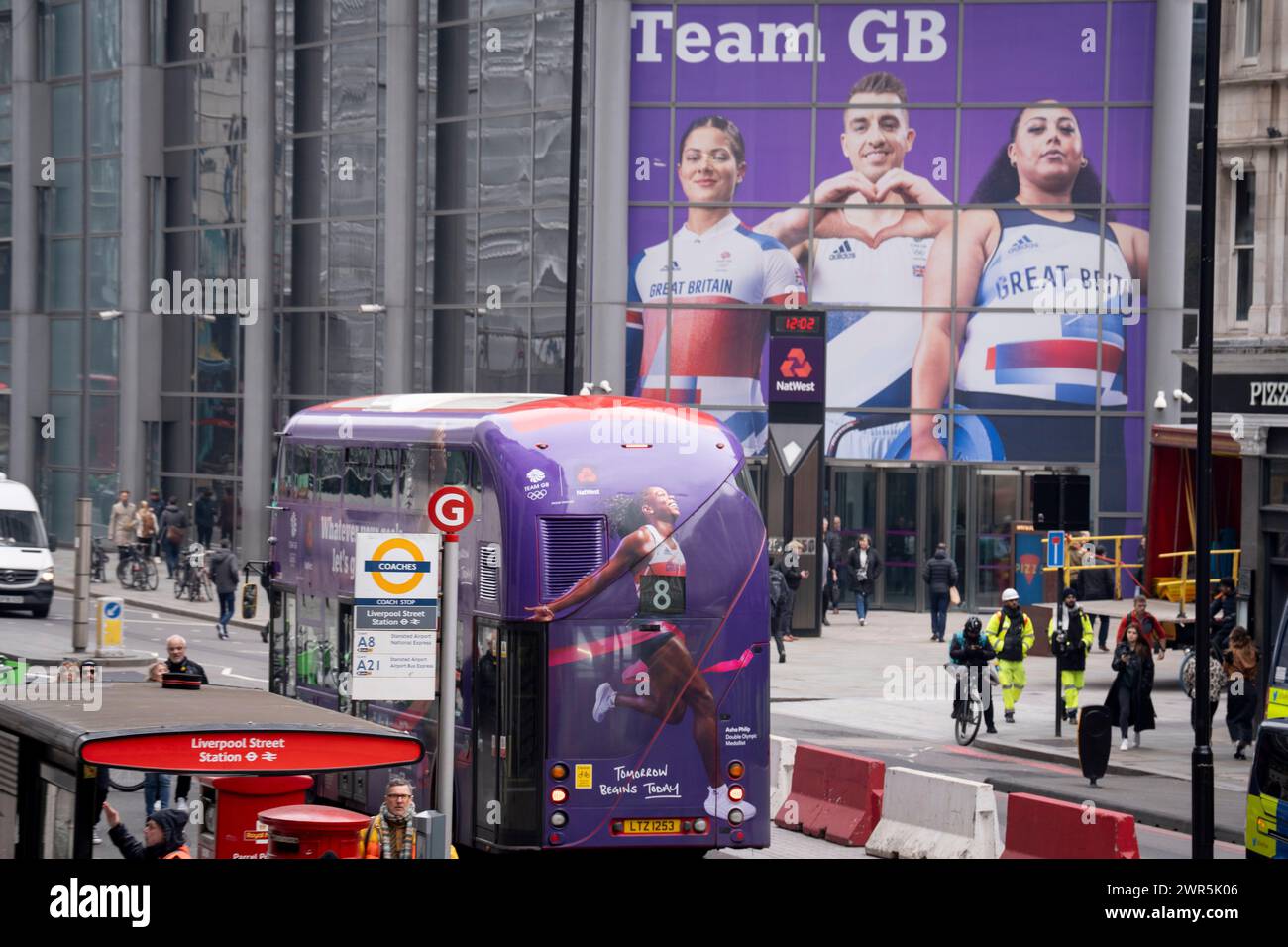 Monate vor den Olympischen Spielen in Paris 2024, übertrifft ein Londoner Bus mit einem Bild von Sprinter Asha Philip ein großes Bild von anderen Team GB Athleten, BMX-Fahrer Beth Shriever, Turner Max Whitlock und Gewichtheber Emily Campbell am Eingang der Natwest Bank in Bishopsgate in London. das Finanzviertel der Hauptstadt am 7. März 2024 in London, England. NatWest und die Coutts Bank sind derzeit offizielle Unternehmenspartner von Team GB. Stockfoto