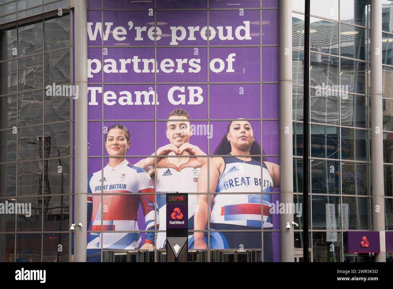 Monate vor den Olympischen Spielen 2024 in Paris, wurde am 7. März 2024 in London ein großes Bild von Athleten des Teams GB, BMX-Fahrer Beth Shriever, Turner Max Whitlock und Gewichtheber Emily Campbell am Eingang zur Natwest Bank in Bishopsgate in der City of London, dem Finanzviertel der Hauptstadt, gesehen. England. NatWest und die Coutts Bank sind derzeit offizielle Unternehmenspartner von Team GB. Stockfoto