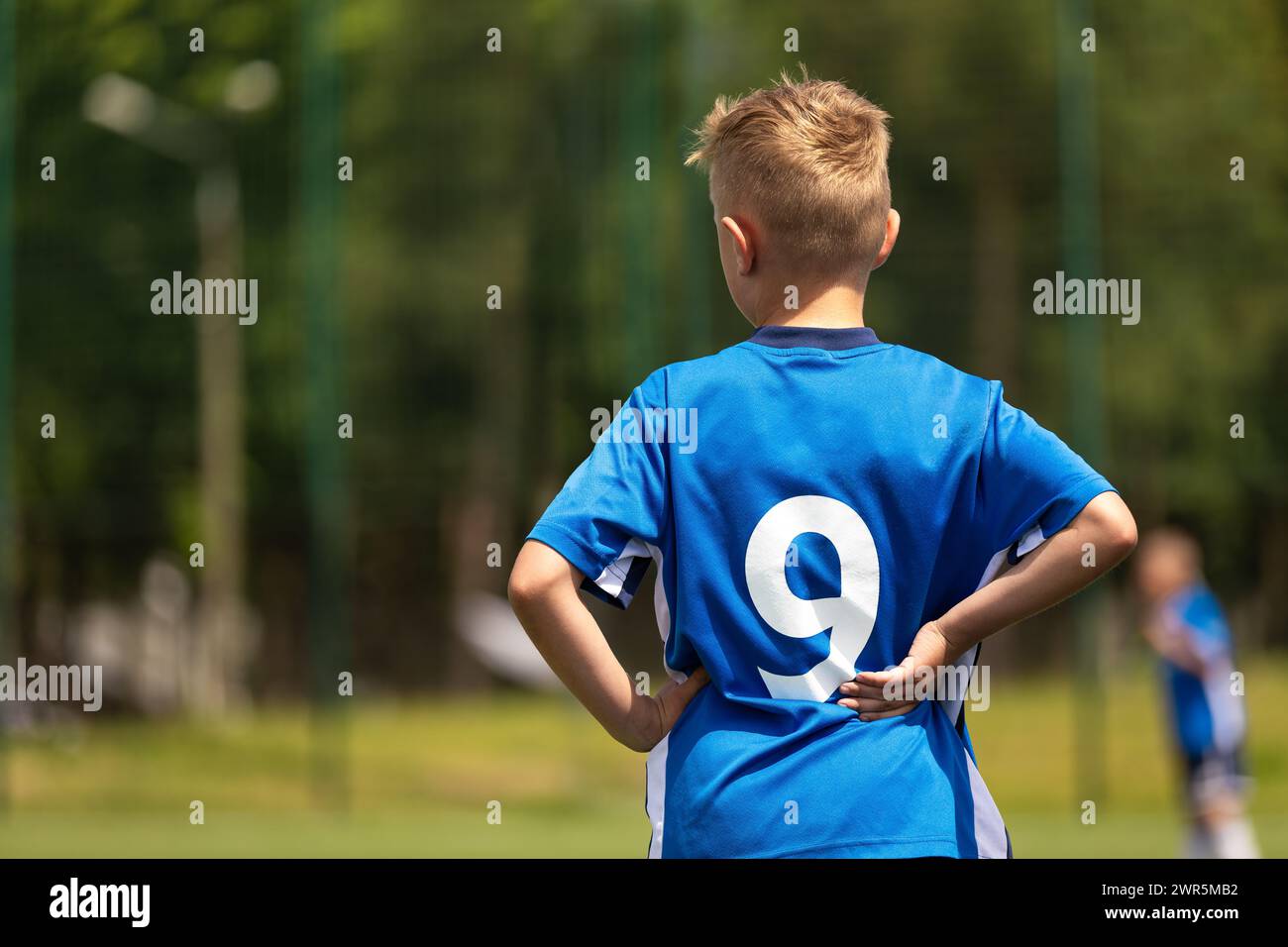 Junge, der mit Teamkollegen Fußball spielt. Der Fußballjunge spielt als Stürmer. Kinder-Fußballmannschaft in einem Fußball-Liga-Spiel. Ein Kind in blauer Fußballuniform wi Stockfoto