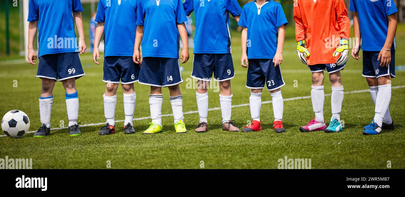 Kinder aus dem Fußballteam stehen in der Schlange. Fußballspieler und Torhüter in blauen Uniformen. Kinder in der Sportmannschaft stehen zusammen. Horizontaler Anschluss Stockfoto