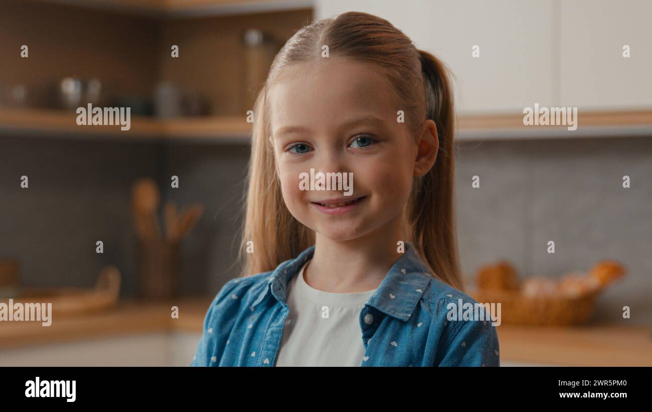 Glückliches positives Porträt zu Hause fröhlich sorglos Kaukasier nettes 10s kleines Mädchen in der Küche lächelnd zahnig aussehende Kamera Schulmädchen Tochter Kind Stockfoto