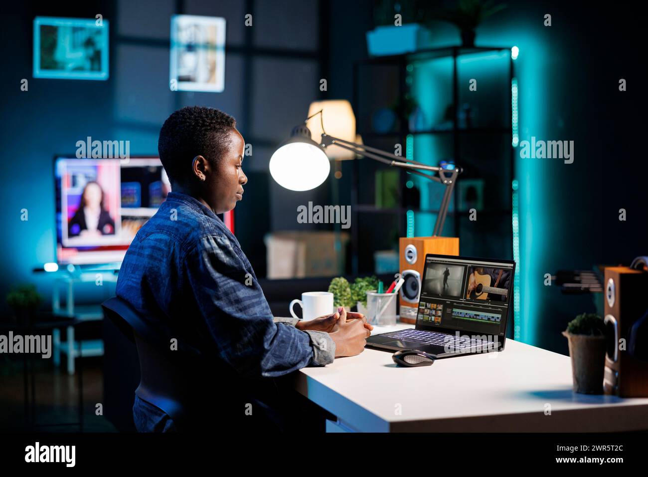 Afroamerikanische Produzentin verwendet digitale Laptops, die für die Erstellung von Inhalten auf dem Schreibtisch platziert werden. Schwarze Frau konzentrierte sich auf den PC und analysierte sorgfältig die Videomontage für die Filmproduktion. Stockfoto