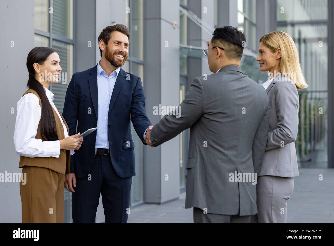 Geschäftstreffen interrassischer Geschäftsleute. Männer und Frauen stehen vor einem Bürozentrum und schütteln die Hand, um sich kennenzulernen und einen Deal zu schließen. Stockfoto