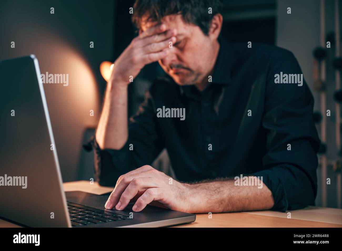 Häufiges Problem mit Fehlfunktionen von Laptops, das einem Geschäftsmann Kopfschmerzen bereitet, während er Überstunden arbeitet, selektiver Fokus Stockfoto