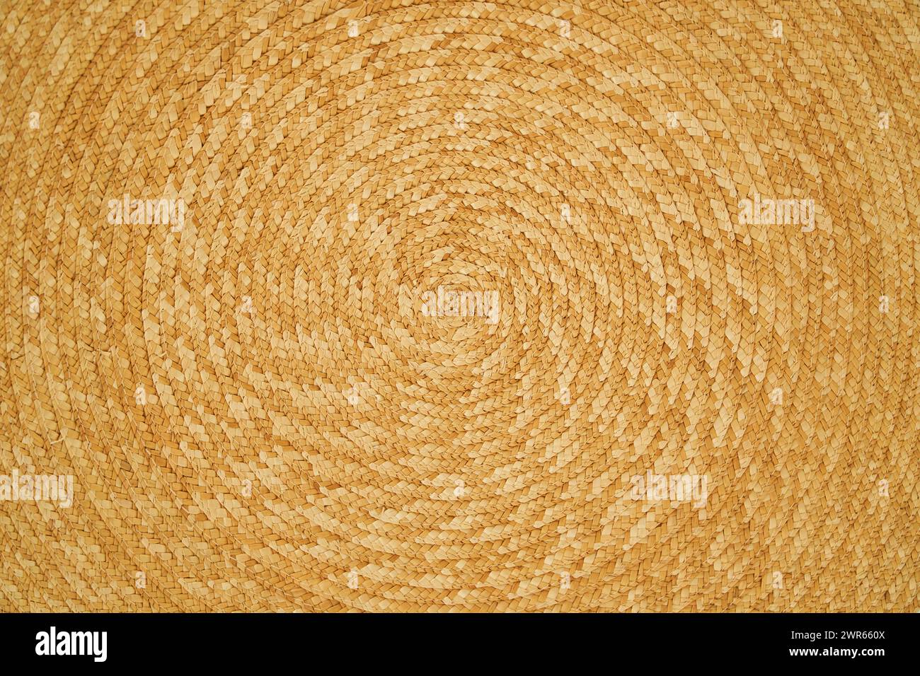 Geflochtener, strukturierter Hintergrund mit Strohstruktur, der eine Spirale bildet Stockfoto