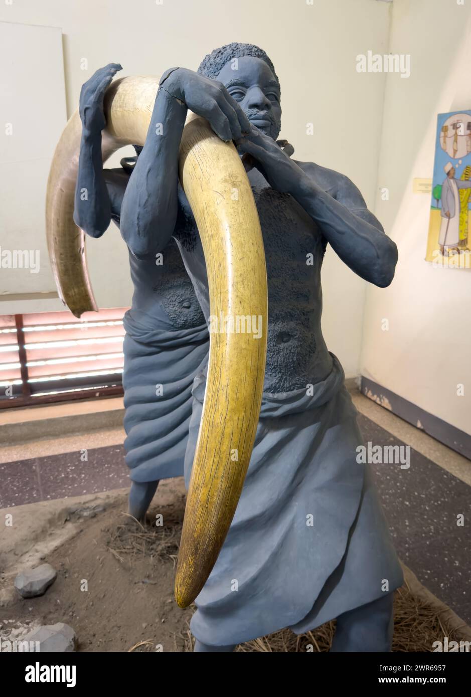 Eine Ausstellung mit afrikanischen Trägern oder Sklaven, die einen riesigen elfenbeinfarbenen Elefantenzahn tragen, Nationalmuseum, dar es Salaam, Tansania Stockfoto