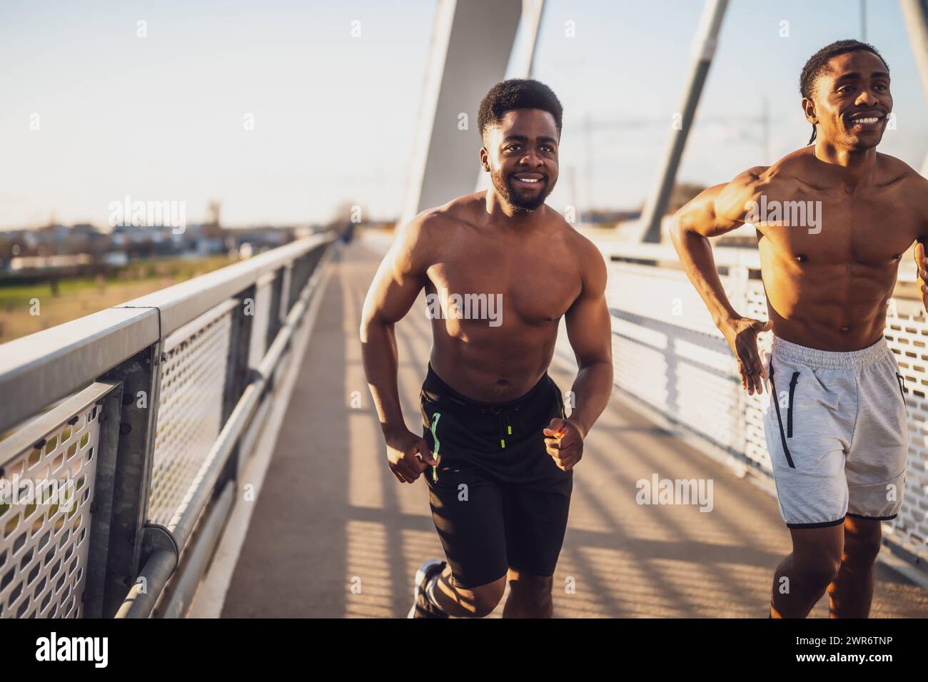 Zwei afroamerikanische Freunde joggen auf der Brücke in der Stadt. Stockfoto