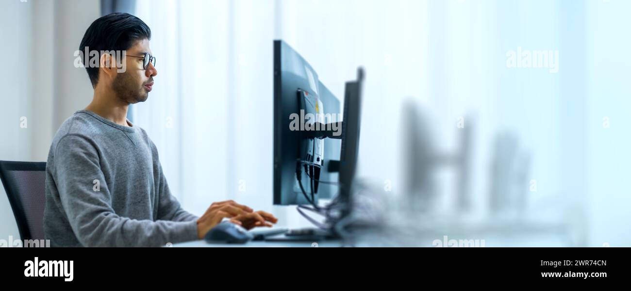 Asiatischer Promt-Ingenieur entwickelt eine Codierungs-App mit Softwaredaten, die vor dem Computermonitor im Büro liegen Stockfoto