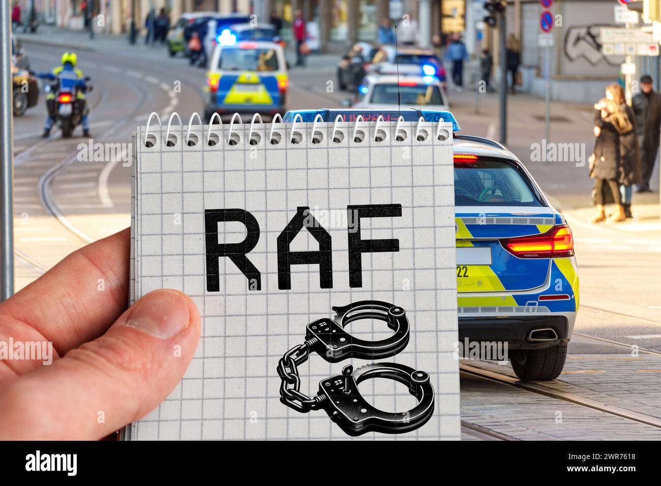 Deutschland - 11. März 2024: Handhalteblock mit Aufschrift: RAF-Rote Armee-Fraktion und Handschellen-Symbol vor Polizeieinsatzfahrzeugen. FOTOMONTAGE *** Hand halten Block mit Aufschrift: RAF Rote Armee Fraktion und Handschellen Symbol für Polizei Einsatzfahrzeuge. FOTOMONTAGE Stockfoto