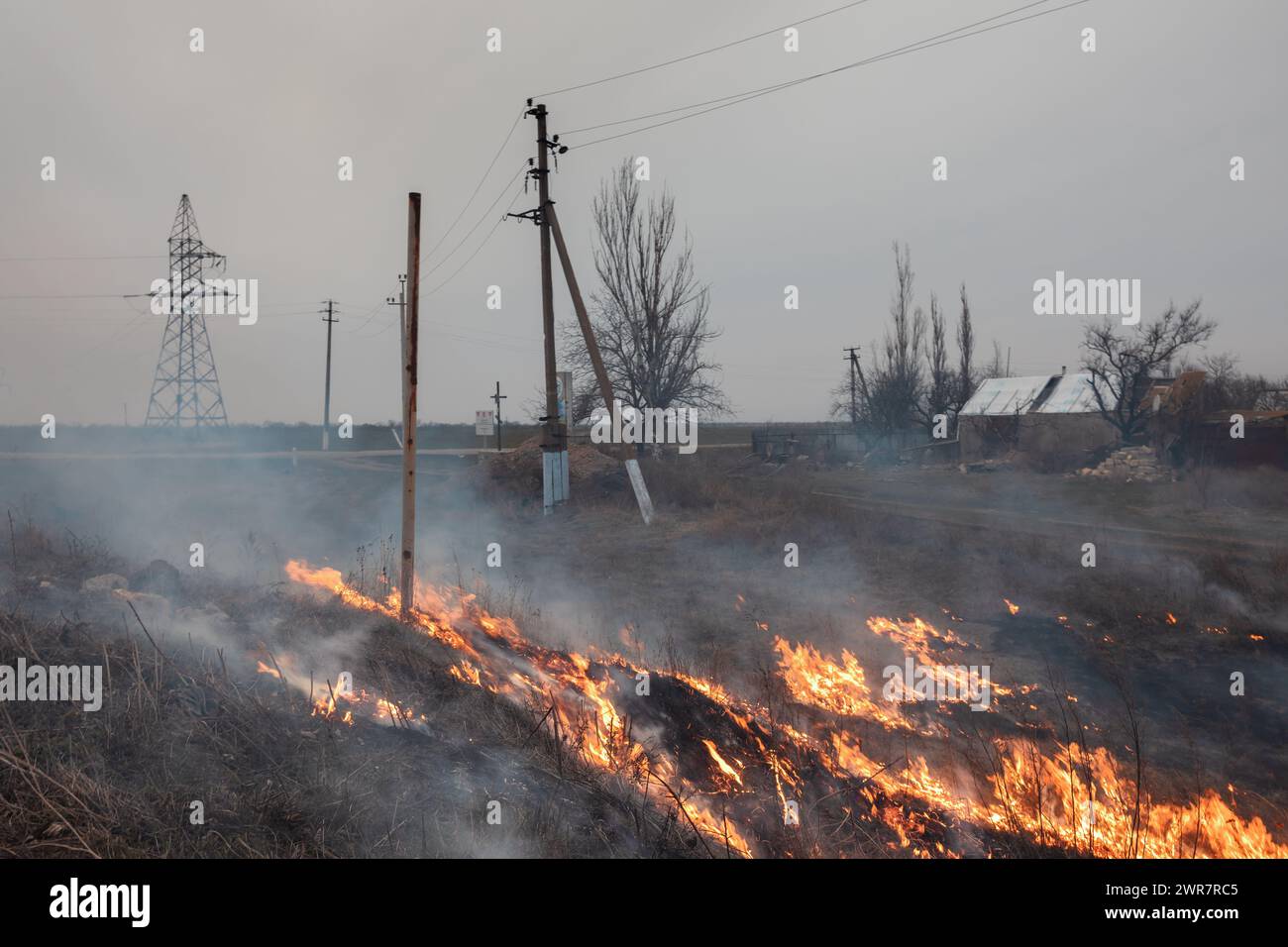 Region Mykolaiv, Ukraine. März 2024. Brennendes Gras ist am Rande eines Dorfes in der Region Mykolajew in der Ukraine zu sehen. Eine typische Szene eines ukrainischen Dorfes in der Region Mykolajew, wie in anderen Regionen der Ukraine nach der Besatzung und in der Nähe der Frontlinie. Regelmäßige Beschießung und Zerstörung von Häusern von Anwohnern. Quelle: SOPA Images Limited/Alamy Live News Stockfoto