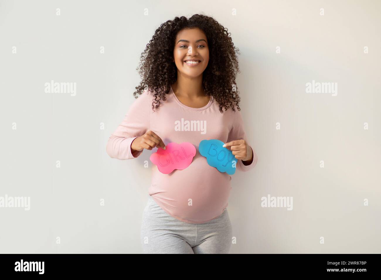 Gender Reveal Party. Glückliche schwarze schwangere Frau mit rosa und blauen Karten Stockfoto