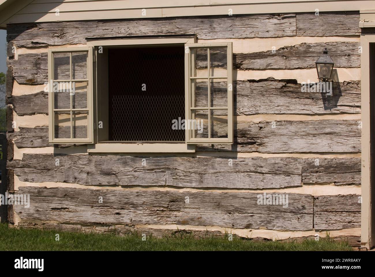 Titel: Offenes Fenster mit Fensterläden an der Außenwand der ursprünglichen Blockhütte quadratische Stämme der alten historischen Scheune aus der Nähe von Holz und kneifende horizontale Form Stockfoto