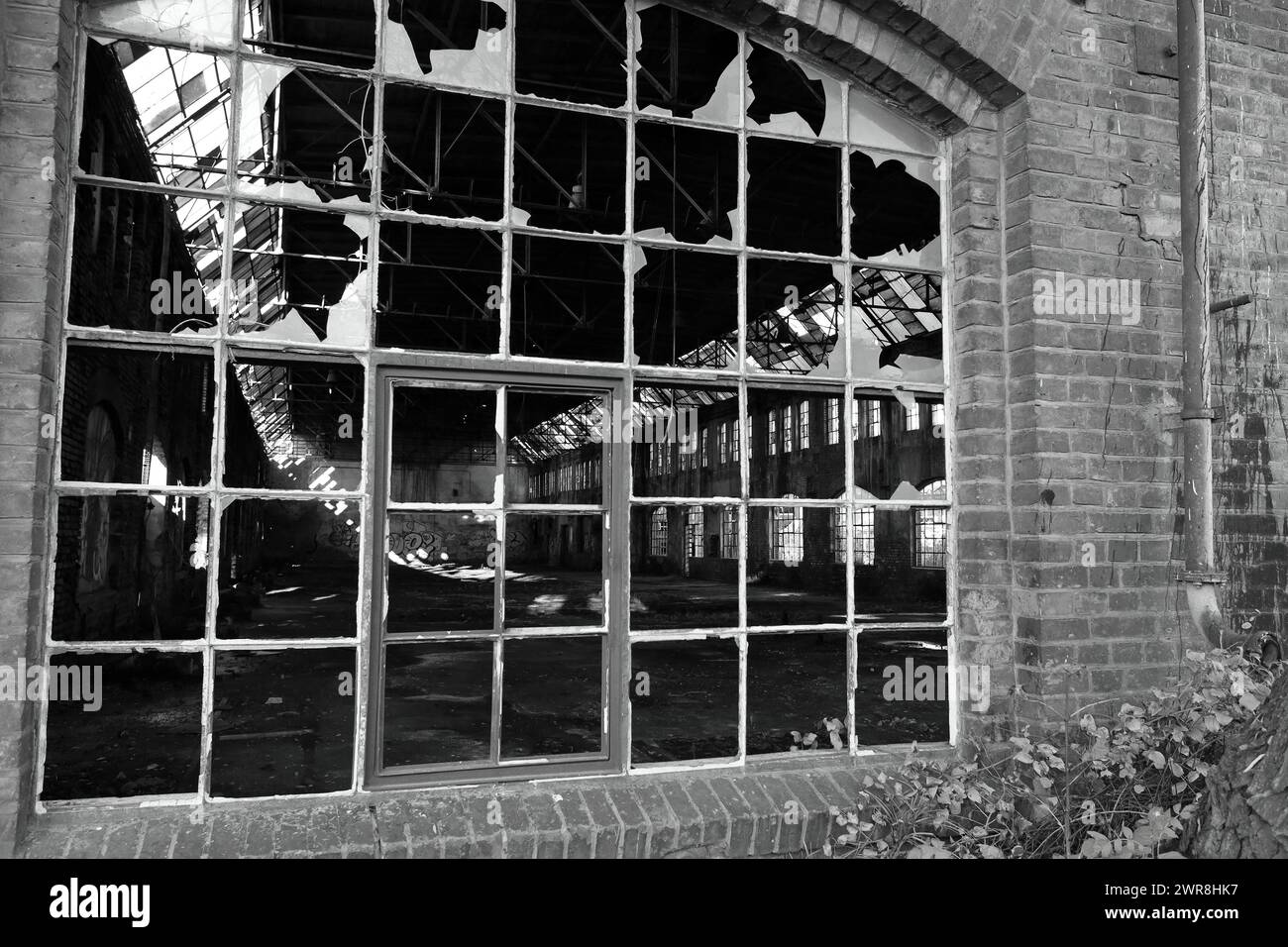 Verlassene und verwüstete Produktionshalle einer Schiffbaufabrik durch kaputte Fenster gesehen. Stockfoto