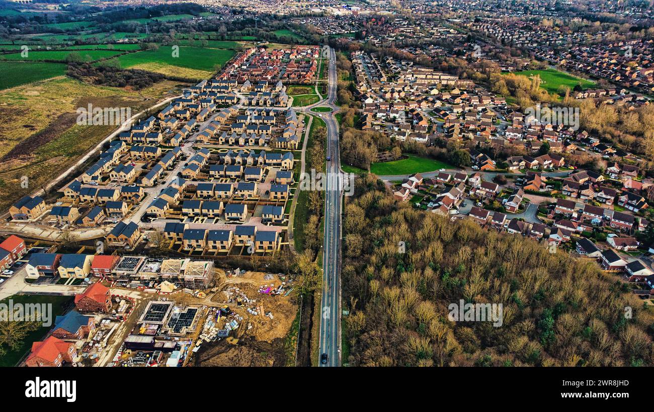 Aus der Vogelperspektive eines vorstädtischen Wohnbaus mit Häuserreihen, kontrastierendem unbebauten Land und Straßen in Harrogate, North Yorkshire. Stockfoto