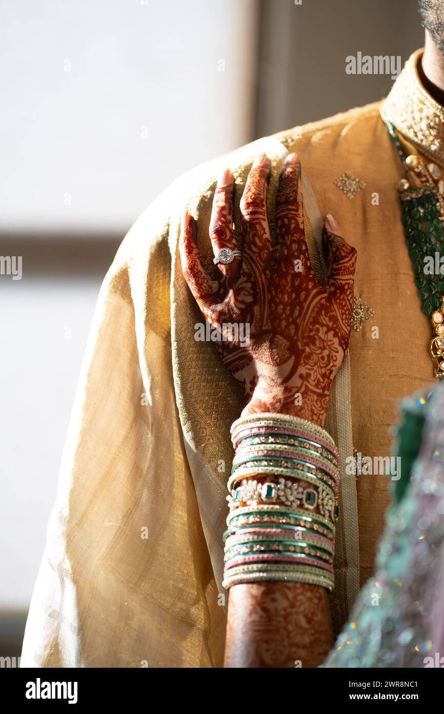 Die Hände eines Bräutigams sind mit verschiedenen Armbändern und Henna-Designs verziert Stockfoto