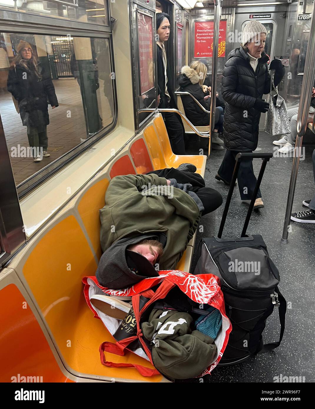 Mann mit Gepäck, der auf der F-Linie in Manhattan auf den Sitzen des U-Bahn-Zuges saß. Stockfoto