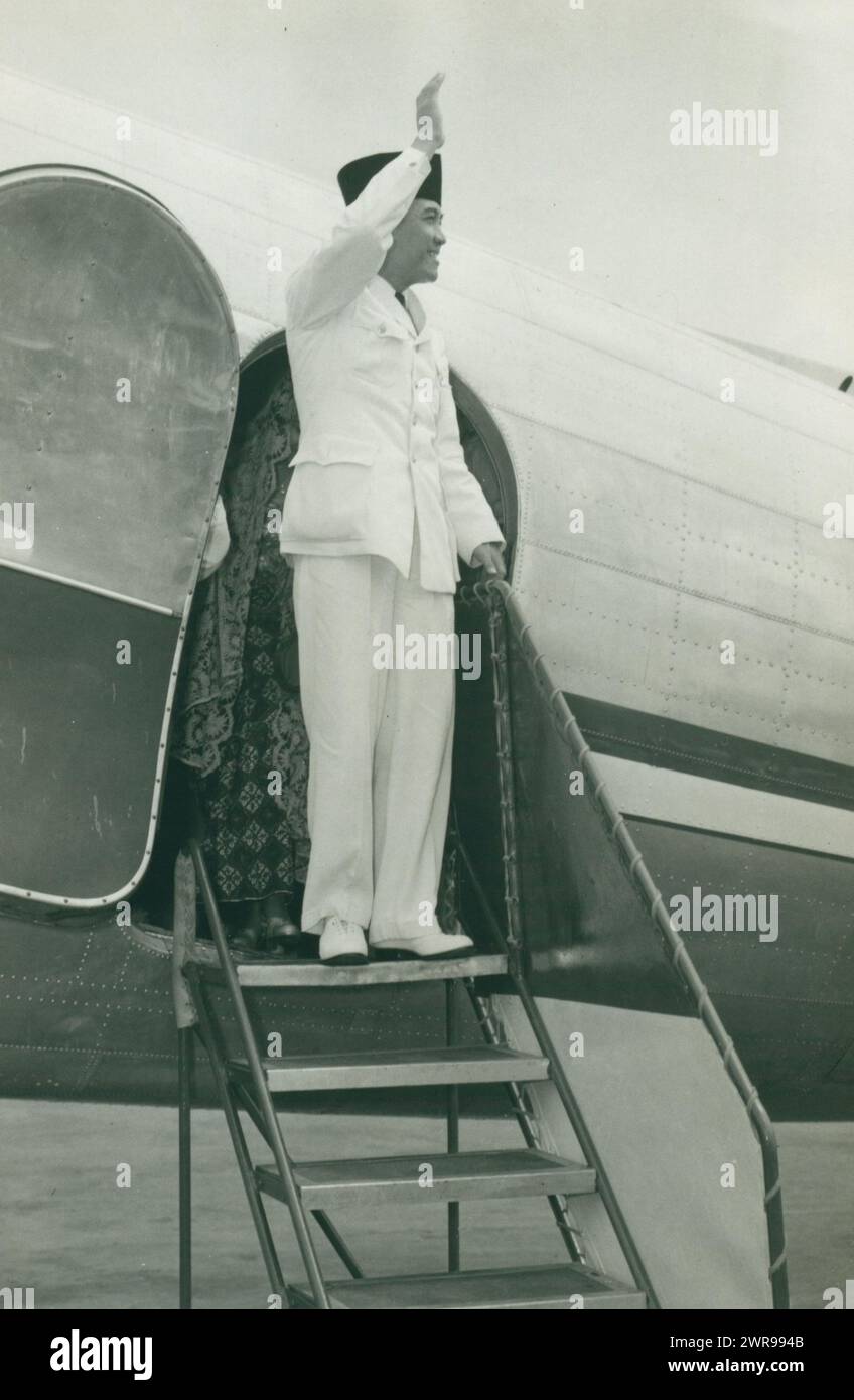 Präsident Sukarno winkt lächelnd von den Stufen eines Flugzeugs. Präsident Sukarno, gekleidet in einem hellen weißen Anzug mit schwarzem Hut, verlässt das Flugzeug lachend und winkt von der Treppe. Willem Boshouwers, Batavia, 1949, fotografische Unterstützung, Breite 12,5 cm x Höhe 19,5 cm, Dokumentarfotos Stockfoto