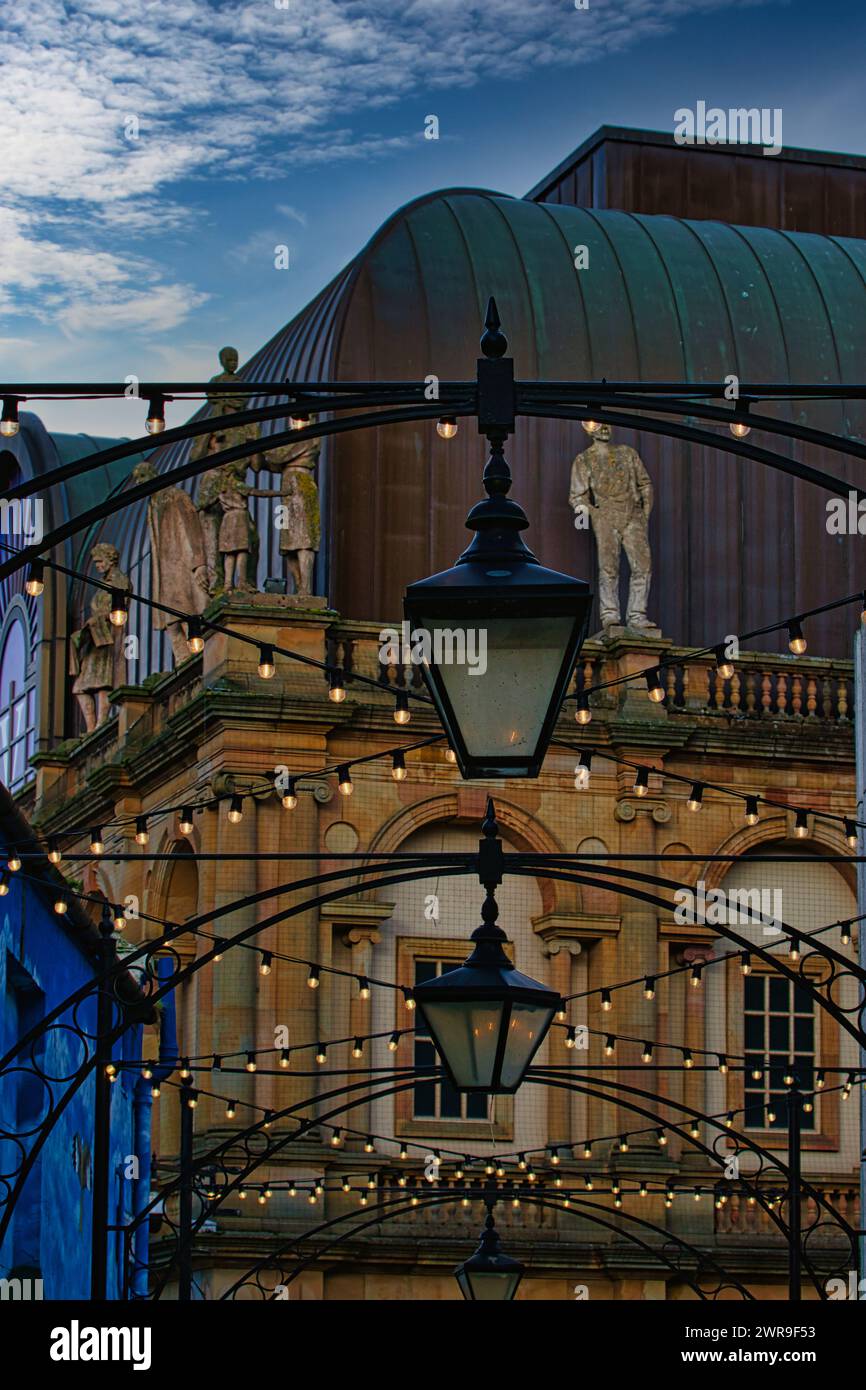 Blick in die Abenddämmerung auf ein klassisches Gebäude mit einer Straßenlaterne im Vordergrund und dekorativen Lichtern, die an eine romantische urbane Szene in Harrogate, England, erinnern. Stockfoto