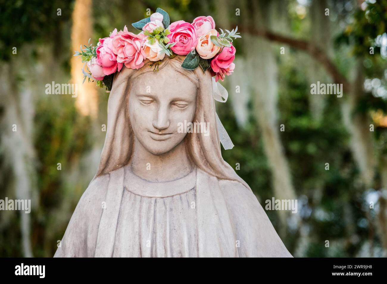 Statue der Jungfrau Maria mit einem Kranz aus rosa Blumen auf dem Kopf Stockfoto