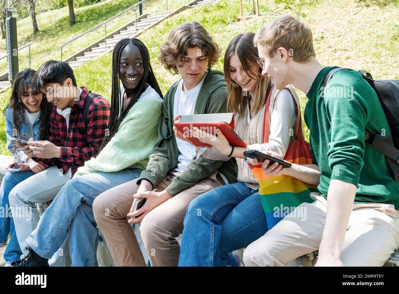 Gruppe junger Freunde, die sich ein Tablet im Freien ansehen – Verbindung und Lernen – Teenager-Schüler, die mit digitalen Bildschirmen interagieren Stockfoto